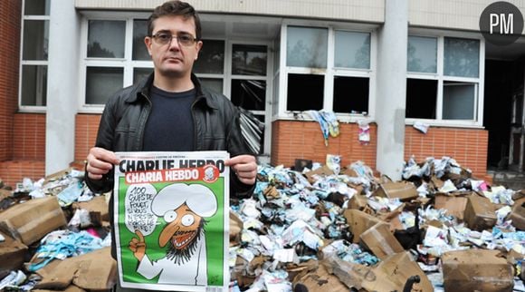 Charb montre la dernière Une de Charlie Hebdo devant les locaux du journal dévastés par un incendie criminel dans la nuit du 1er au 2 nnovembre 2011.