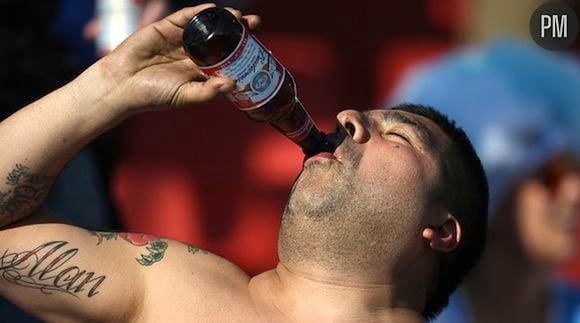 Un supporter de football boit une bouteille de Budweiser dans les tribunes de la Coupe du monde, en 2010